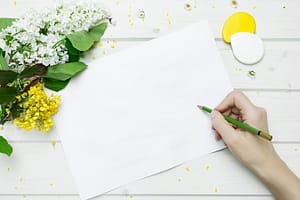 Blank spring checklist with fresh flowers and pencil on white wood