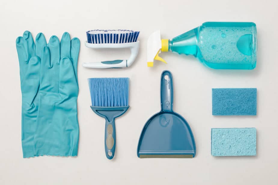 Flat lay of must-have essential cleaning tools like brush, gloves, and spray bottle