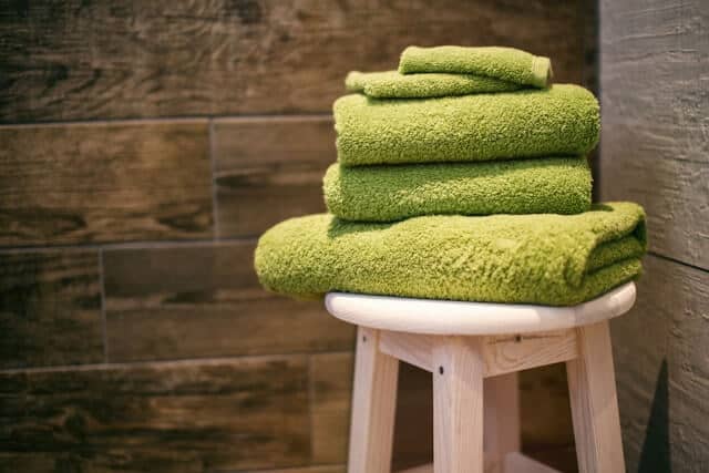 Towels stacked on a stool as part of a spring cleaning guide for the home